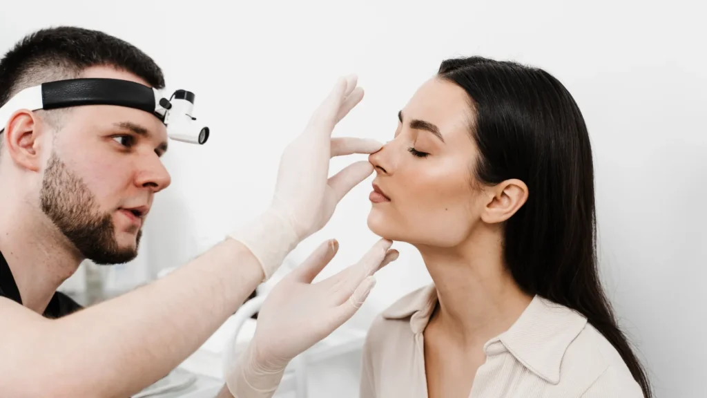 Surgeon explaining different types of rhinoplasty and nasal reshaping techniques using a realistic 3D anatomical nose model.